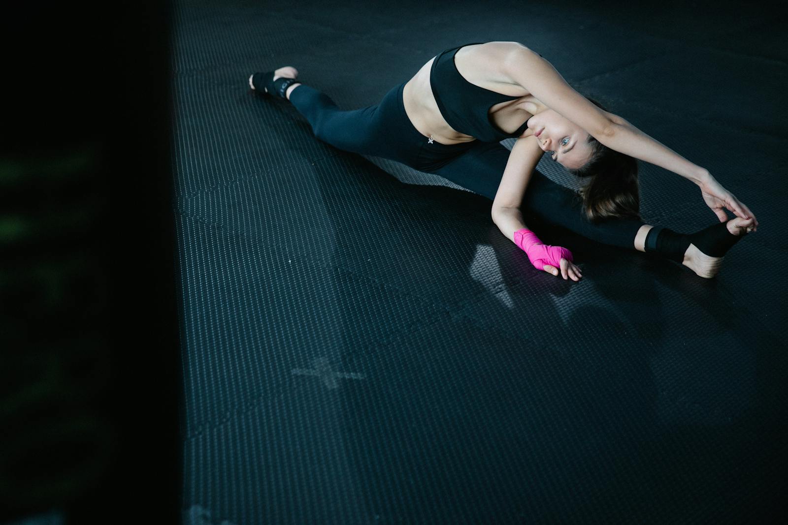 A woman performs a stretching exercise on a gym mat, showcasing flexibility.